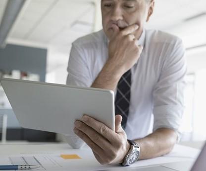 Man, thinking and examining a computer screen.