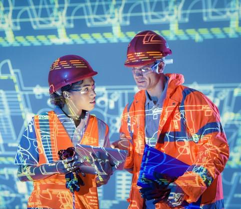 Two workers in high visibility gear talk tech.