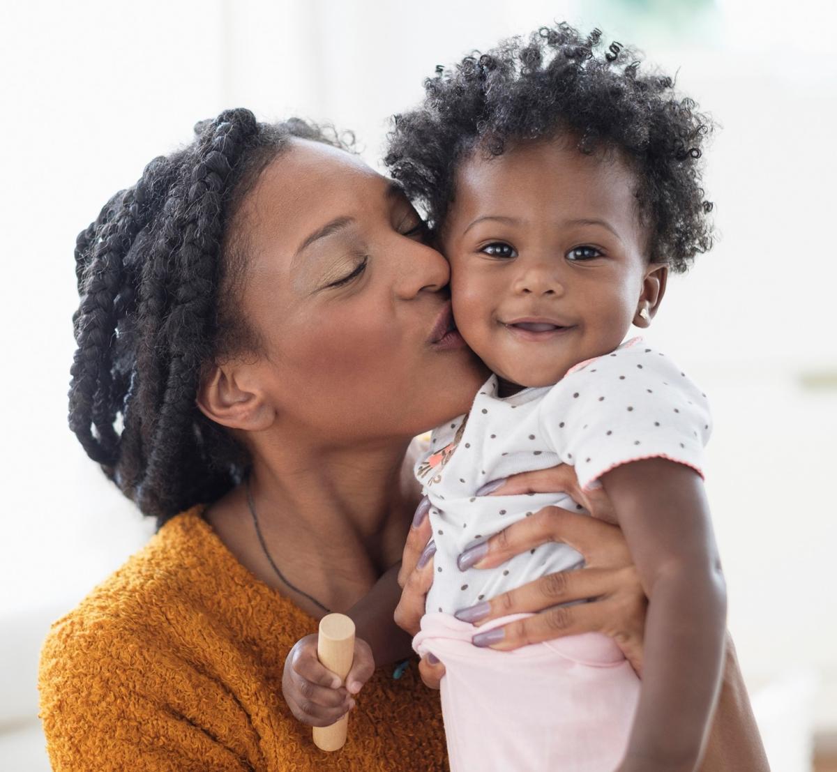 Woman of color kisses her child.