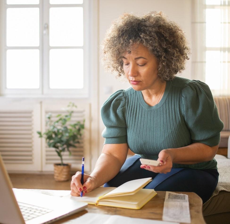 Woman of color studies at a laptop.