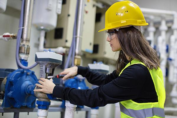 Female engineer checks a pressure valve.