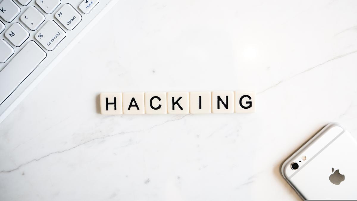 Scrabble tiles on a white surface spell "Hacking."